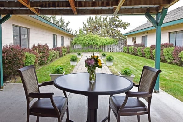 Table with flowers on a patio surrounded by greenery