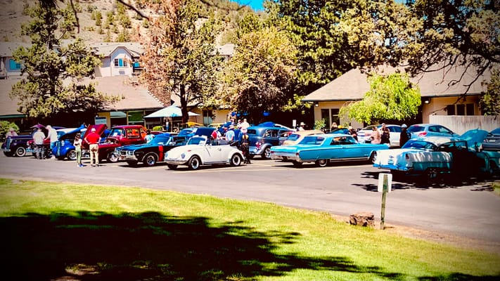 Outdoor classic car show with several vintage cars and attendees.