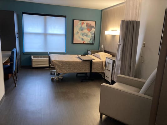 A spacious and well-lit resident room with a bed, desk, and seating area