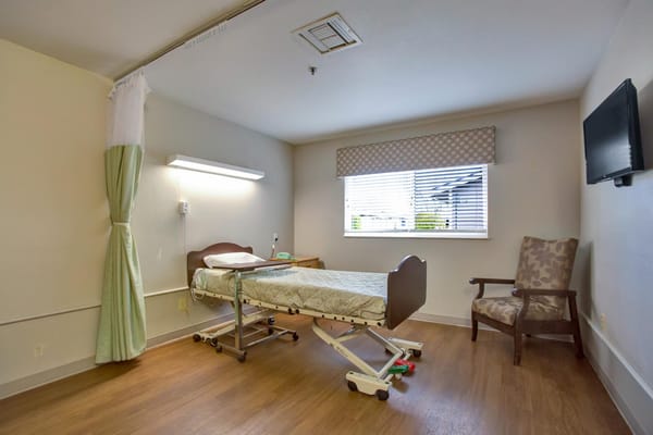 Private room in a senior care facility with hospital bed