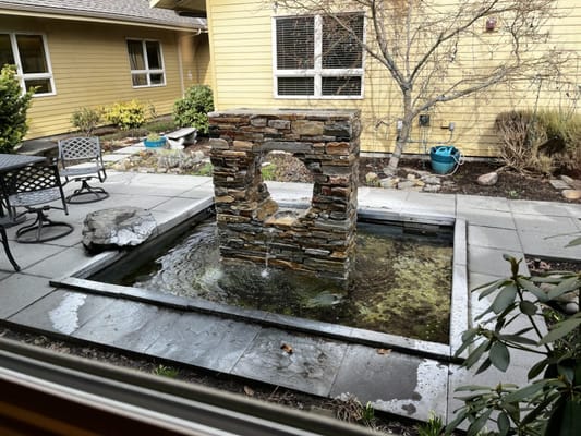 Stone water feature in a courtyard with seating area
