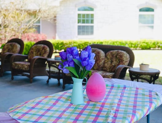 A table with flowers and a pink Easter egg in an outdoor seating area