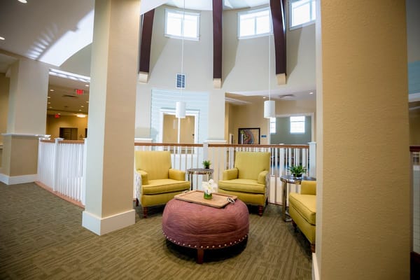 Cozy lounge area with yellow chairs and a round ottoman