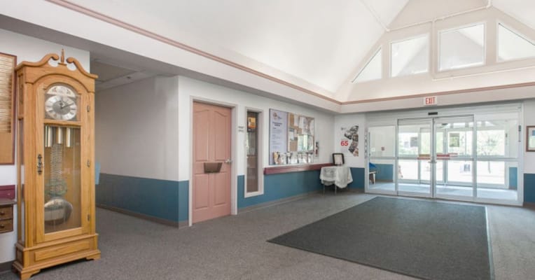 Interior lobby area with wooden clock and pink door.