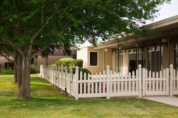 Exterior of Sandstone Pioneer Trail senior living facility with a white picket fence.