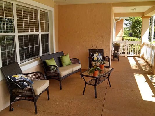Comfortable seating area on a porch with potted plants.