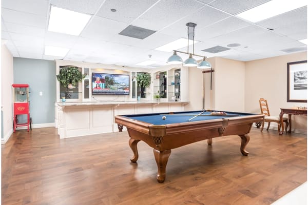 Billiards table in a well-lit room with a television and seating.