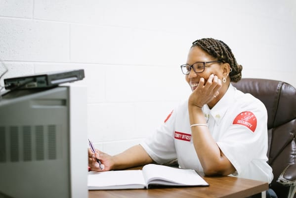 Security officer smiling while writing notes at a desk