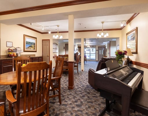 A cozy common area featuring wooden dining furniture and a piano.
