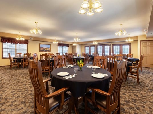 Dining room with wooden chairs and tables set for meals.