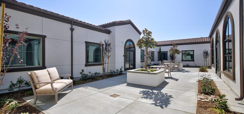 Outdoor courtyard with seating and greenery at Temecula Memory Care
