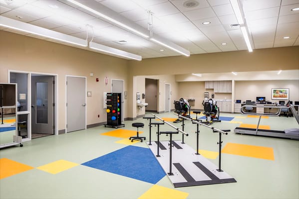 Rehabilitation room featuring therapy equipment and colorful flooring.