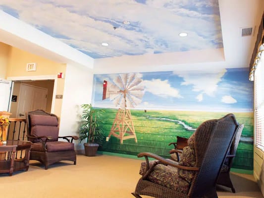 Cozy lounge area featuring a scenic mural of a windmill and green fields.