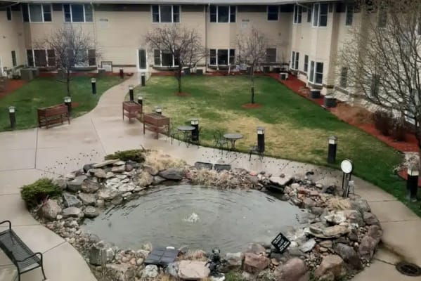 Tranquil pond surrounded by benches and pathways in senior living facility
