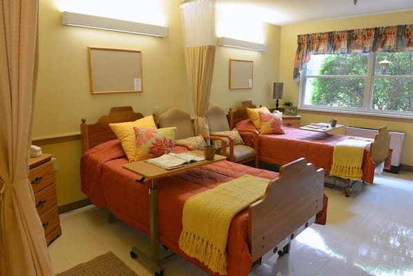 A cozy shared bedroom with two beds, colorful pillows, and a small table.