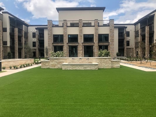 Lush green courtyard with a stone feature and surrounding buildings