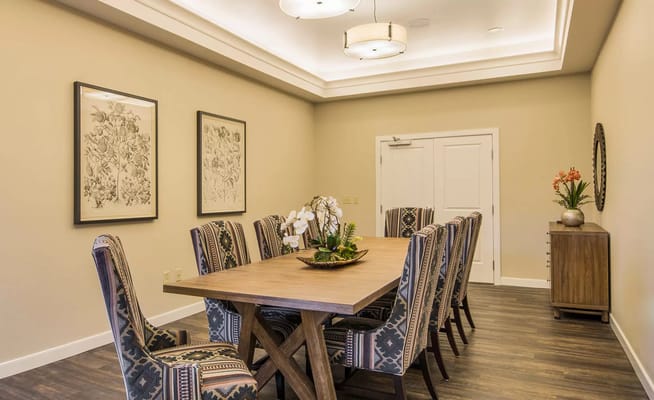 Dining table surrounded by patterned chairs in a well-lit dining room.