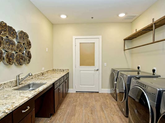 Modern laundry room with stainless steel appliances and a granite countertop