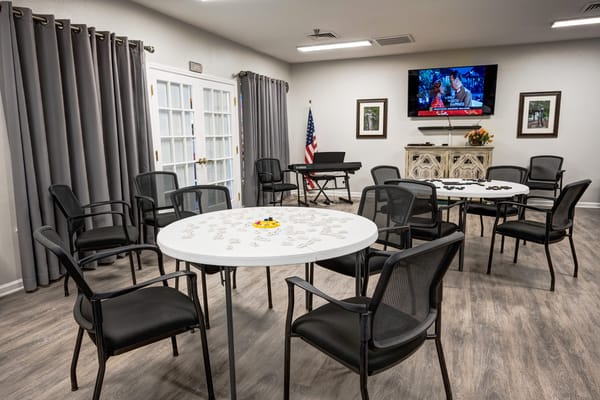 Common room with tables and chairs, television, and piano