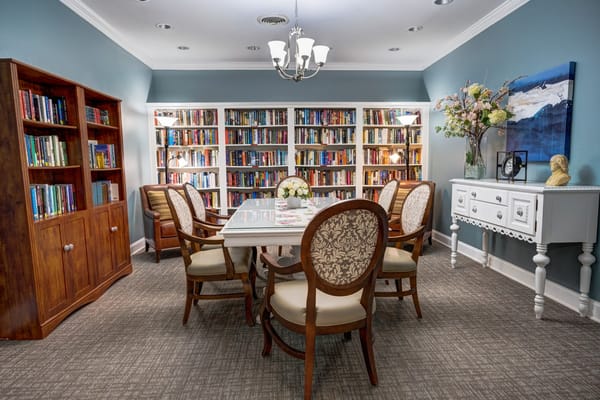 Dining table surrounded by chairs in a cozy library setting.