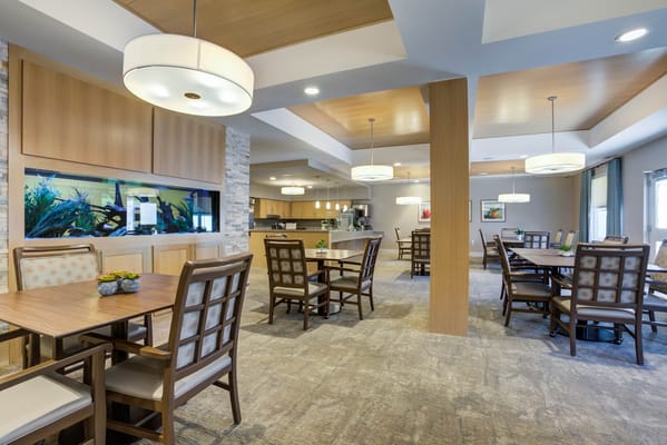 Bright dining area with tables and chairs alongside an aquarium.