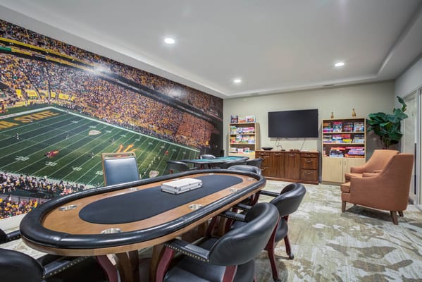 A cozy gaming room with a poker table and a large mural of a football stadium.