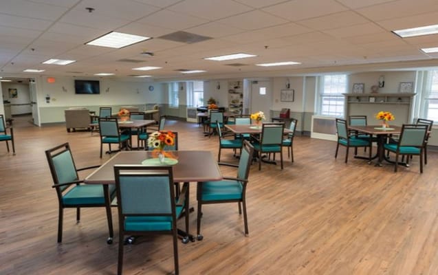 Spacious common area with tables and chairs in a senior living facility.