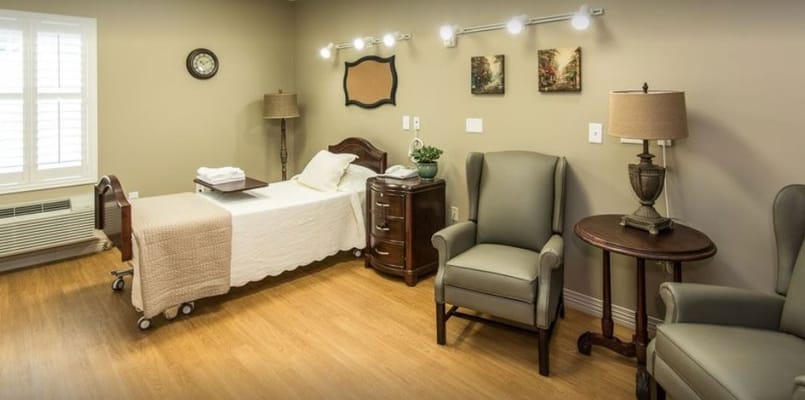 A well-furnished bedroom with a bed, two chairs, and storage furniture.