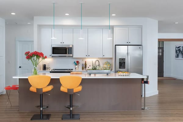 Bright kitchen with orange bar stools and flowers on the counter