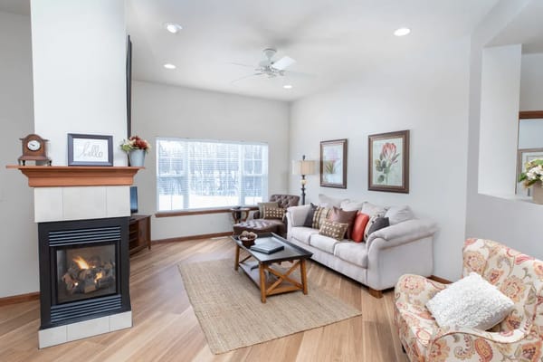 A cozy living room with a fireplace, sofa, and large windows