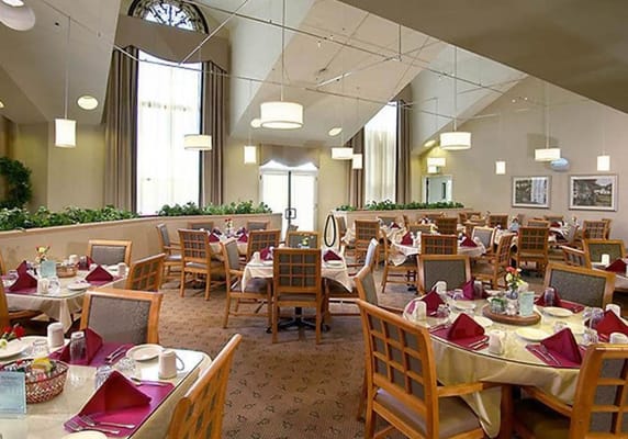 Spacious dining room with tables set for meals and large windows