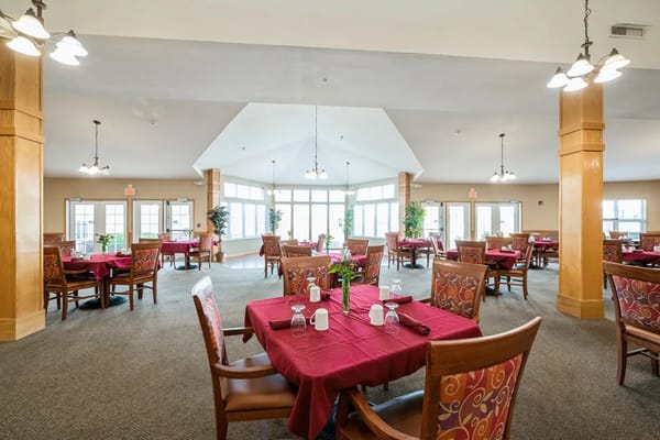 Cozy dining room with red tablecloths and floral centerpieces at Trustwell Living.