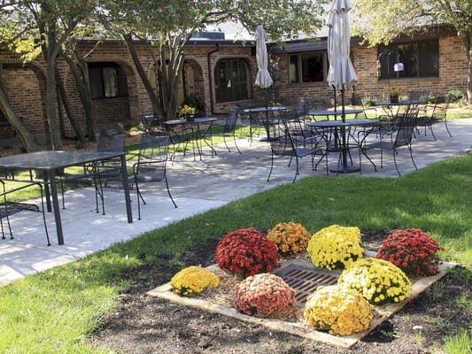 Scenic outdoor seating area with tables, umbrellas, and colorful flowers.