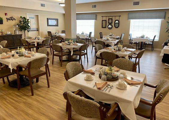 Cozy dining room set with tables, floral centerpieces, and place settings.