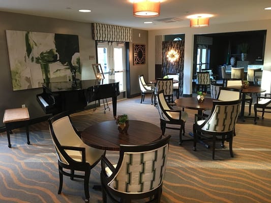 Cozy lounge area with tables, chairs, and a piano