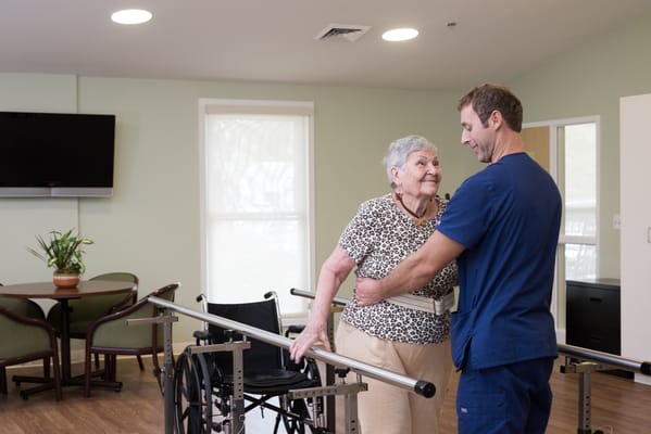 A staff member assisting a resident in an activity room