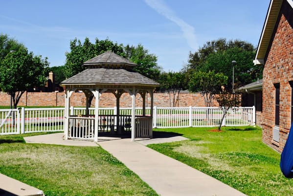 A wooden gazebo surrounded by green grass and trees at Winters Park.
