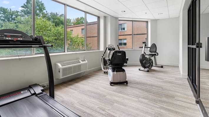 Well-lit exercise room with treadmill and stationary bike