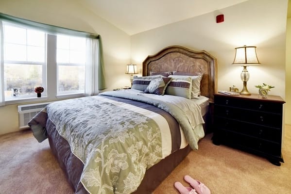 A cozy resident room with a bed, lamps, and decor