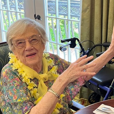 Elderly woman smiling with a yellow flower lei