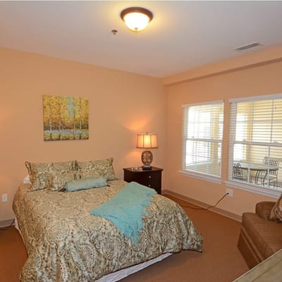 A cozy resident room with a bed and armchair