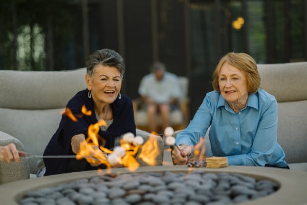 Two women roasting marshmallows by a fire pit