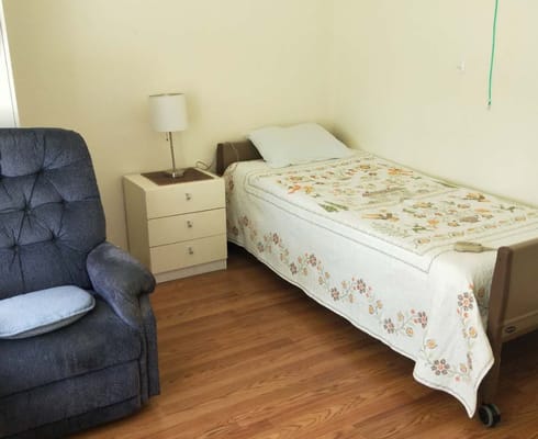 Cozy room with a bed and chair in a care facility
