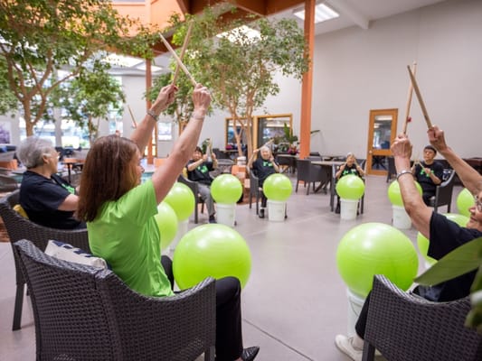 Residents participating in a seated drumming activity indoors