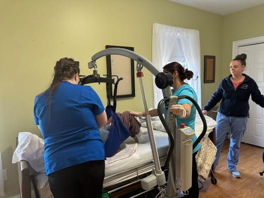Staff assisting a resident with a lift in a bedroom