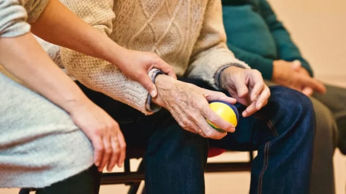 A caregiver assisting an elderly resident with a ball