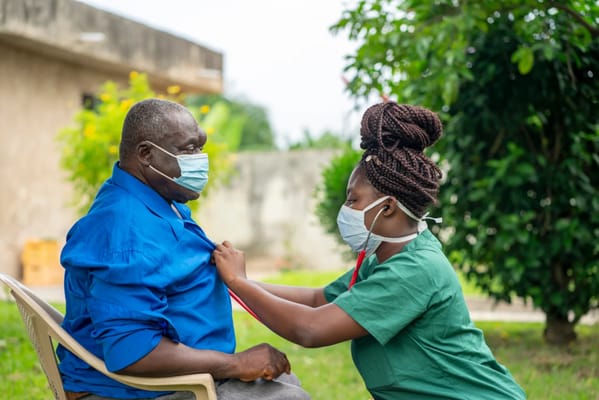 Healthcare worker assisting an elderly man outdoors