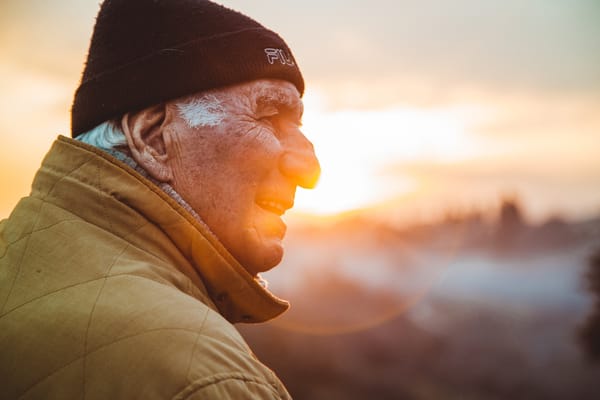 An elderly man smiling during sunset