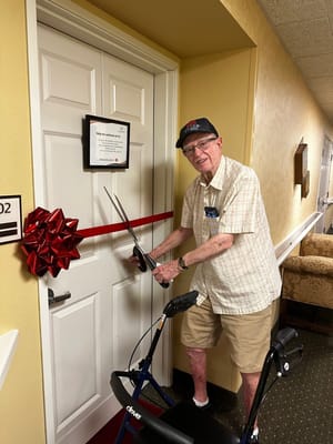 Resident preparing to cut a ribbon on a new room entrance