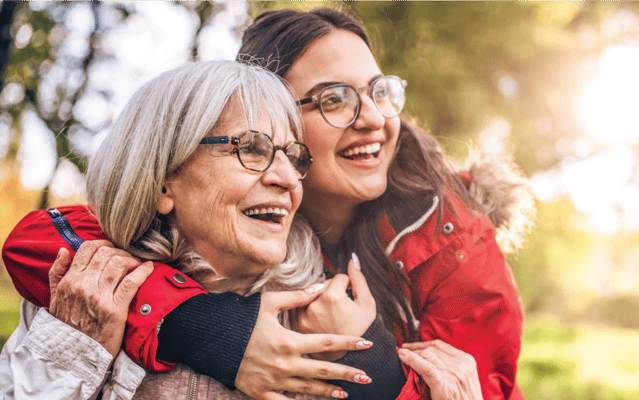 A young woman hugging an elderly woman outdoors